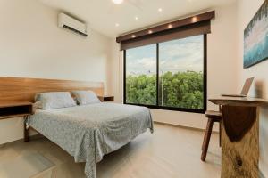 um quarto com uma cama e uma grande janela em Cenote Korima - Relax in Paradise - Stunning House with Pool em Cancún