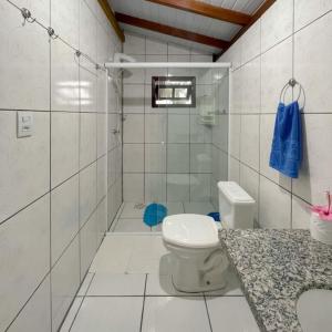 a white bathroom with a toilet and a shower at Moradas do Maneca in Imbituba +125 photos