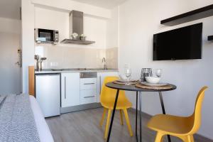 a small kitchen with a table and two yellow chairs at Estudio Frankie in L'Escala