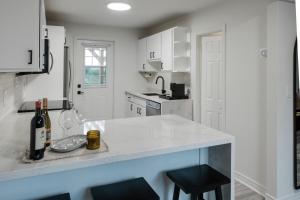 a white kitchen with a counter with a bottle of wine at The Little White Haus in Niagara-on-the-Lake