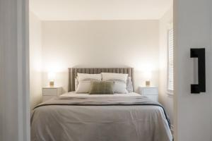 a white bedroom with a large bed with two lamps at The Little White Haus in Niagara on the Lake