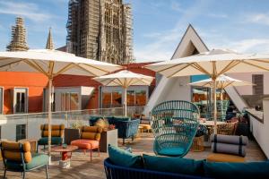 eine Terrasse mit Stühlen, Tischen und Sonnenschirmen in der Unterkunft Motel One Ulm in Ulm