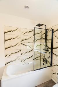 a bathroom with a tub and a glass wall at 2 Bedroom House By Maison Stays - Free Parking in Nottingham