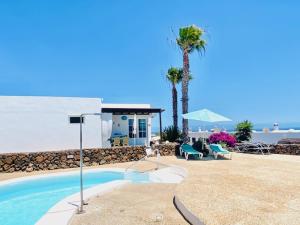 uma piscina com cadeiras e uma casa e palmeiras em Bungalow Rey Carlos em Puerto del Carmen
