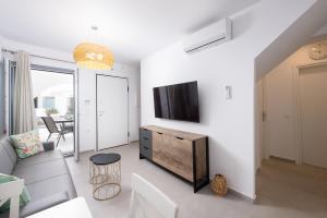 a living room with a couch and a tv on a wall at Private Pool Holiday Home by Sunshine Place World in Ano Mera