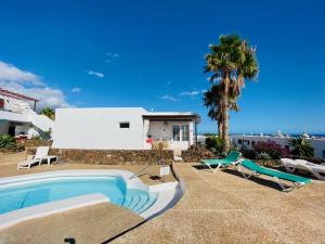 uma piscina com duas espreguiçadeiras e uma casa em Bungalow Rey Carlos em Puerto del Carmen