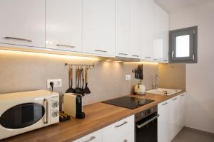 a kitchen with white cabinets and a microwave at Private Pool Holiday Home by Sunshine Place World in Ano Mera