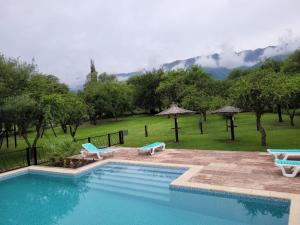a swimming pool with chairs and a view of a mountain at El Naranjero Apart in Carpintería