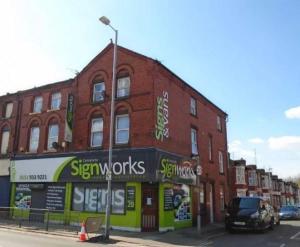 a brick building on a street with a car parked in front at Litherland Apartment in Litherland