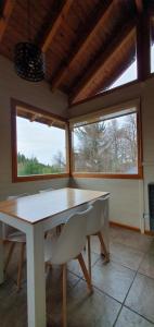 a dining room with a table and two windows at Cabaña Victoria I in San Martín de los Andes