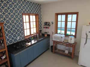 a kitchen with blue cabinets and a white refrigerator at Casa 1 Chalé Alto dos Bandeirantes in Tiradentes