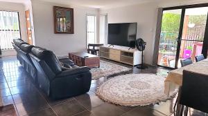 a living room with black leather chairs and a flat screen tv at Kumera Home in Gold Coast