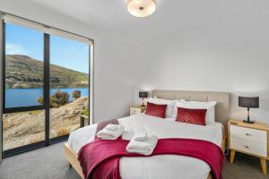 - une chambre avec un grand lit et une grande fenêtre dans l'établissement Residence du Lac by Staysouth, à Queenstown