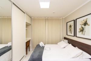 a hotel room with two beds and a mirror at Edifício Metropolitan Barcelona - Jardim Goias - MBC in Goiânia