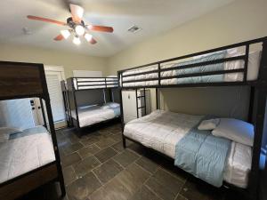 a room with three bunk beds and a ceiling fan at MyCrib Houston Hostel in Houston