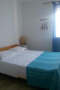 1 dormitorio con 1 cama con manta azul y blanca en Secluded fisherman's cottage Cove Zincena, Pasman - 12982, en Tkon
