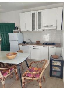 cocina con armarios blancos, mesa y sillas en Secluded fisherman's cottage Cove Zincena, Pasman - 12982, en Tkon