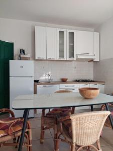 una cocina con armarios blancos y una mesa con sillas. en Secluded fisherman's cottage Cove Zincena, Pasman - 12982, en Tkon