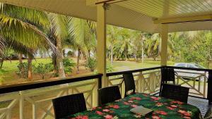 a porch with a table and chairs and palm trees at HUAHINE - Hibiscus House in Haapu