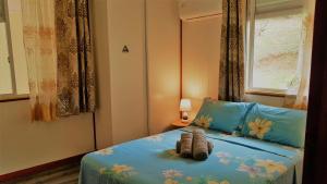 Un dormitorio con una cama azul con un animal de peluche. en HUAHINE - Hibiscus House, en Haapu