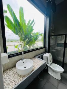 a bathroom with a sink and a toilet and a window at ริมยมรีสอร์ท in Ban Wang Din