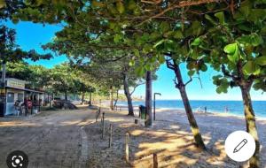 a beach with trees and the ocean in the background at Casa de Praia da Lara in Piúma