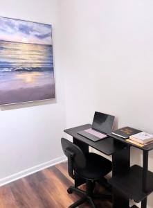 una scrivania con un computer portatile in una stanza con un dipinto di Modern comfort at The Domain Austin ,Texas ad Austin