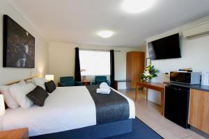 Habitación de hotel con cama grande y TV en Windmill Motel & Events Centre en Mackay
