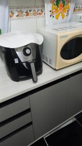a toaster oven sitting on a counter next to a microwave at Apto da Andreia in Praia Grande