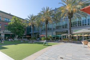 um grande edifício com palmeiras e pessoas sentadas na relva em 1 Bedroom Apt near Santana Row, recently remodeled em San José