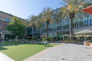 a large building with palm trees and people sitting on the grass at 1 Bedroom Apt near Santana Row, recently remodeled in San Jose