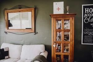 a living room with a white couch and a wooden cabinet at The Historic Old Pharmacy Hockeys - Millthorpe in Millthorpe