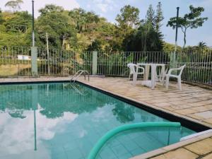 a pool with a table and chairs next to a fence at Cantinho da Vovó Regina in Miguel Pereira