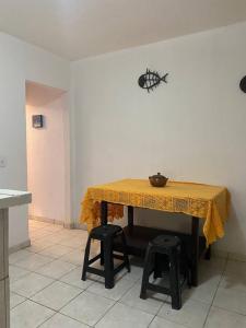 uma mesa com uma toalha de mesa amarela e dois bancos em Morada dos Ventos em Fortaleza