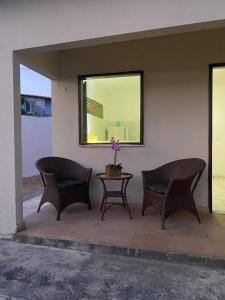 três cadeiras e uma mesa com uma flor num pátio em Morada dos Ventos em Fortaleza
