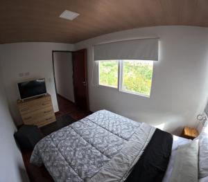 1 dormitorio con 1 cama, TV y ventana en La Loma en Villa Giardino