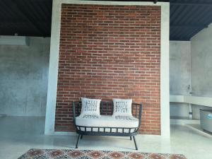 ławka z dwoma poduszkami przed ścianą z cegły w obiekcie Nia room w mieście Kerobokan