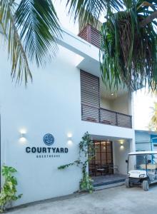 フラにあるCourtyard Guesthouseの中庭を読む看板付き白い建物