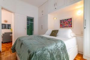 a white bedroom with a bed and a painting on the wall at Vinicius de Moraes Ipanema Apartment in Rio de Janeiro