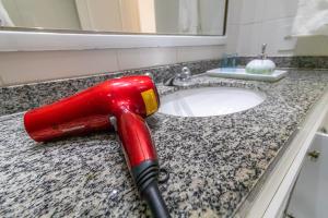 a red blow dryer on a bathroom sink at Vinicius de Moraes Ipanema Apartment in Rio de Janeiro +38 photos
