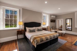 Quamby Estate في Hagley: غرفة نوم بسرير وكرسي ونوافذ