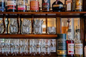 ein Regal mit Gläsern und Flaschen Alkohol in der Unterkunft Quamby Estate in Hagley