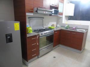 a kitchen with a stainless steel stove and wooden cabinets at apartamento san martin in Quito