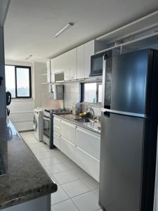 uma cozinha com armários brancos e um frigorífico de aço inoxidável em Maravilhosa cobertura duplex vista mar em Salvador