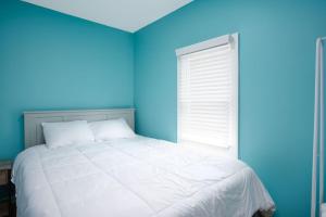 a blue bedroom with a white bed and a window at Buckeye Lake Cottage in Hebron