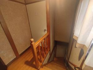 a hallway with a wooden stairway with a wooden railing at Guesthouse Kincha 駅東口 in Utsunomiya