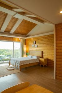 1 dormitorio con cama y ventana grande en Green Narae Pension, en Seogwipo