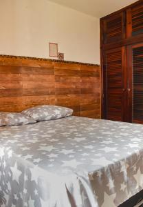 1 dormitorio con 1 cama con cabecero de madera en Recanto da Árvore Suítes, en Arraial do Cabo