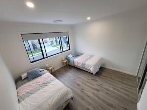een slaapkamer met 2 bedden en een raam bij New 5 bedroom house in Rousehill in Riverstone