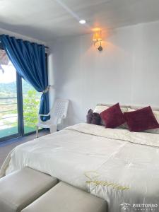 Un dormitorio con una gran cama blanca y una ventana en Phutonso Homestay, en Chiang Mai